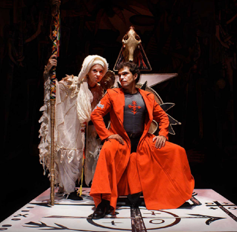 "Fuenteovejuna" - a man in an orange robe speaking with a woman in a white outfit