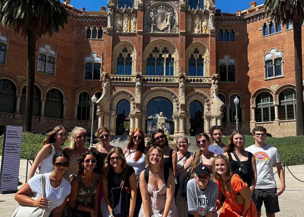 students posing in front of the entrance to the Hospital de la Santa Creu i Sant Pau, which features elaborate stonework and colorful mosaics.