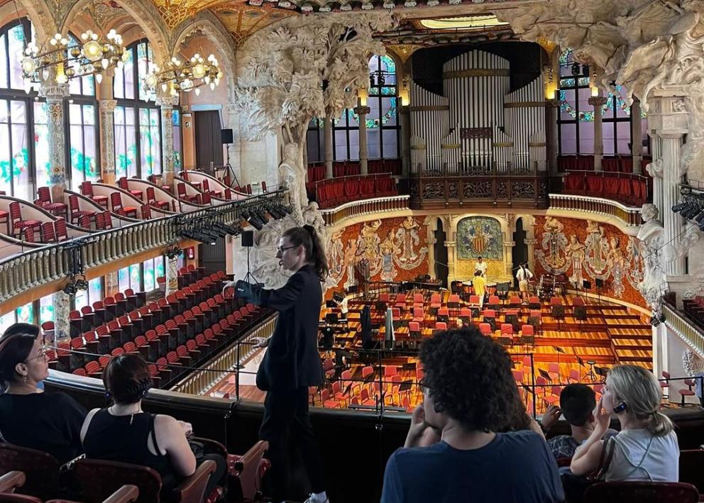 Students inside the Palau de la Música Catalana, looking at stained-glass skylight and ornate decorations