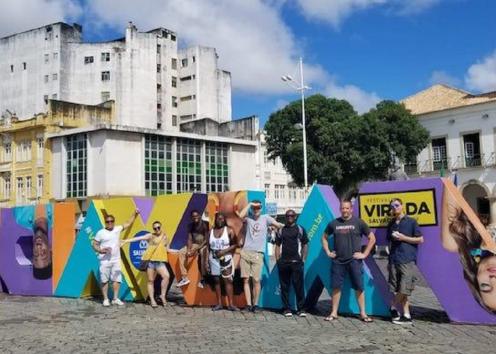 Group photo of students and professors studying abroad in Brazil, posing by a colorful statue