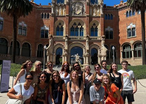 students posing in front of the entrance to the Hospital de la Santa Creu i Sant Pau, which features elaborate stonework and colorful mosaics.
