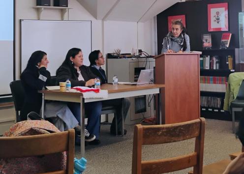 Professor at podium near students who are about to present their panel